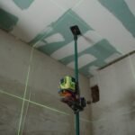 A laser level tool in action at an indoor construction site with marked walls.